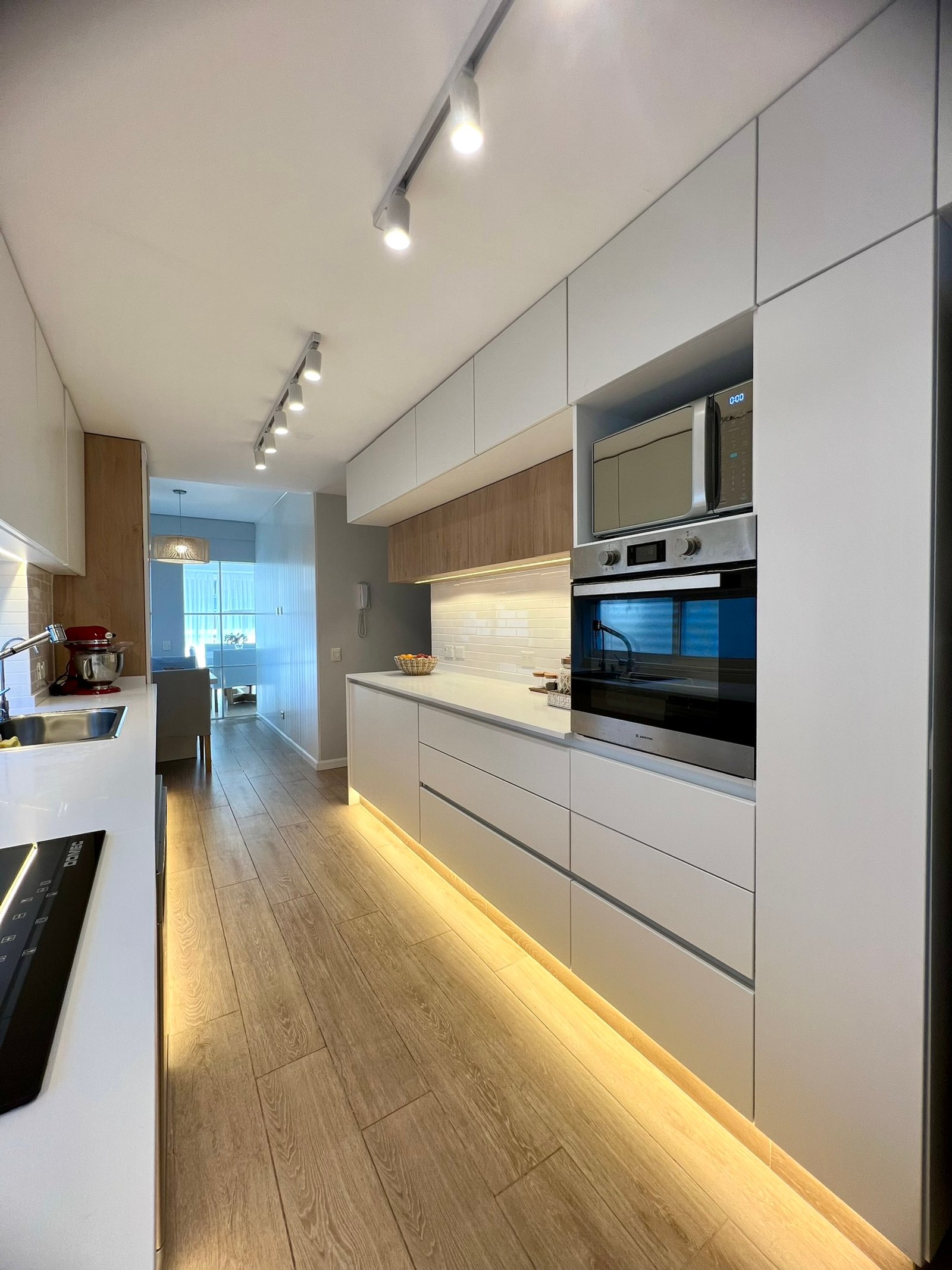 Cocina moderna blanca minimalista con iluminación indirecta y madera — proyecto Araoz, por MDBK Arquitectura, en Palermo