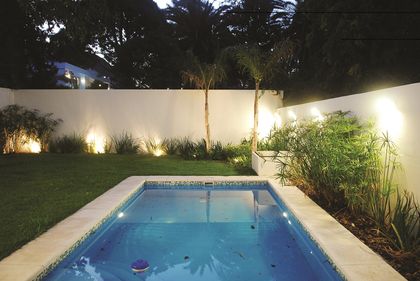 Pileta rectangular iluminada en patio minimalista con muros blancos — proyecto Reformas Urbanas, por Ciba Arquitectura