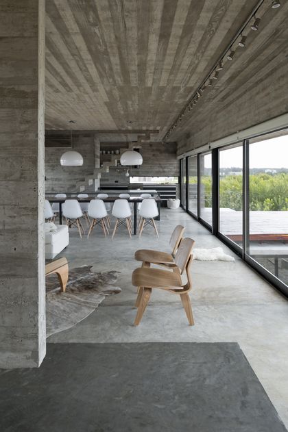 Comedor moderno en hormigón visto con ventanal y sillas de diseño — proyecto Casa Golf, por Luciano Kruk