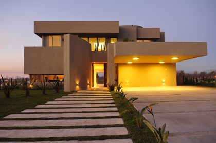 fachada moderna con camino de losas de hormigón — proyecto Moderna Seducción, por Apaarquitectura, en Tigre