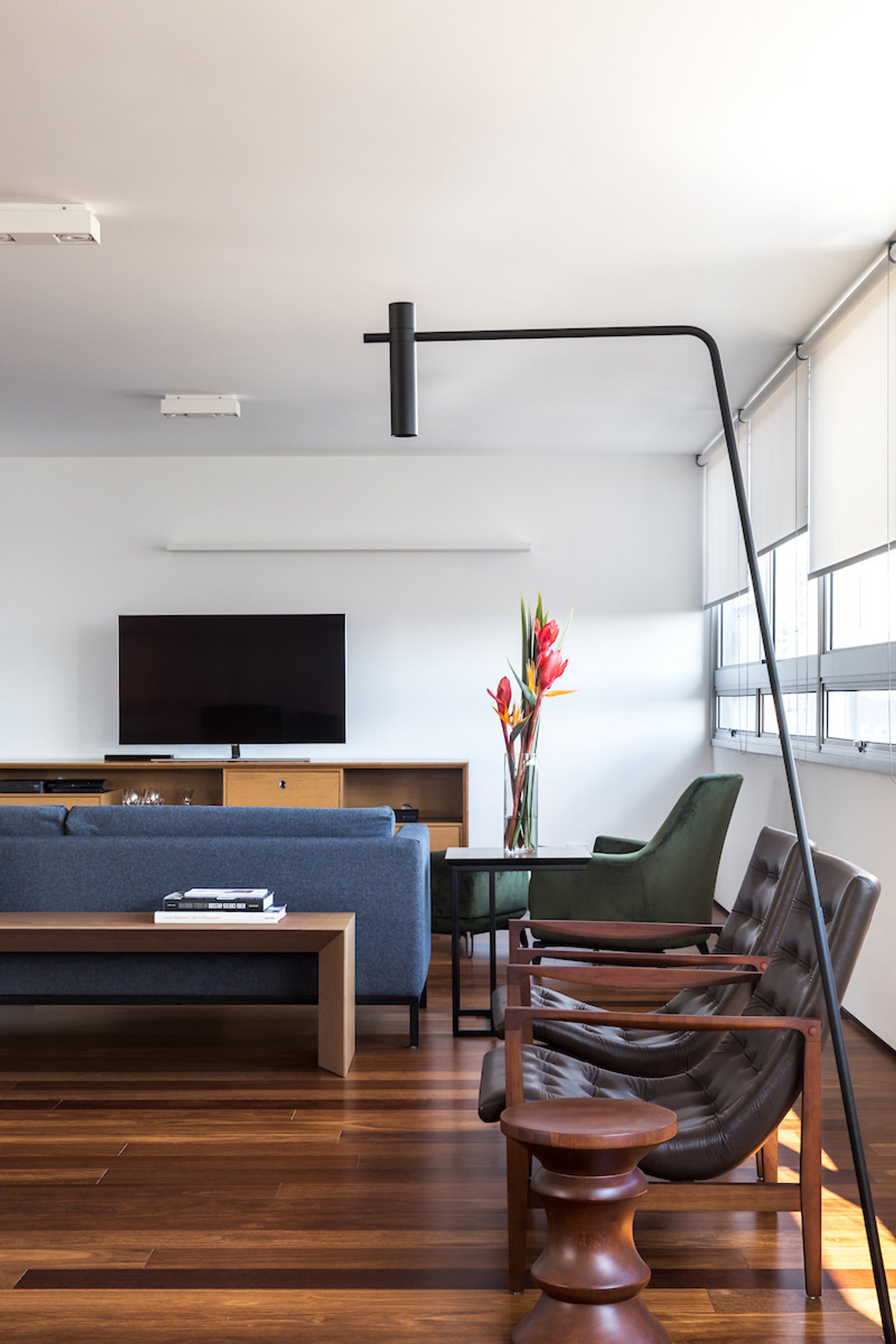 Ampla sala de estar e jantar com poltronas mid-century e luminária de chão preta — projeto Apartamento JB, por Boscardin Corsi Arquitetura