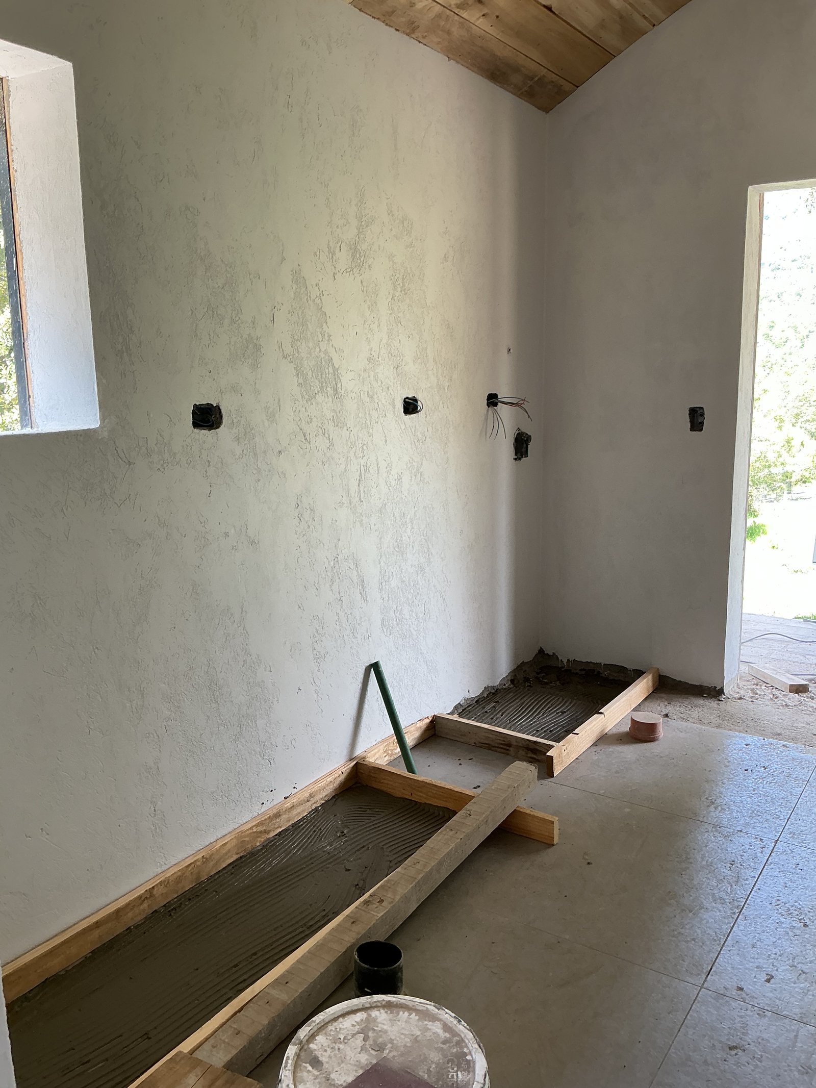 espacio en construccion con vigas de madera y microcemento — proyecto Valle escondido, por Design & Living, en San Martín de los Andes