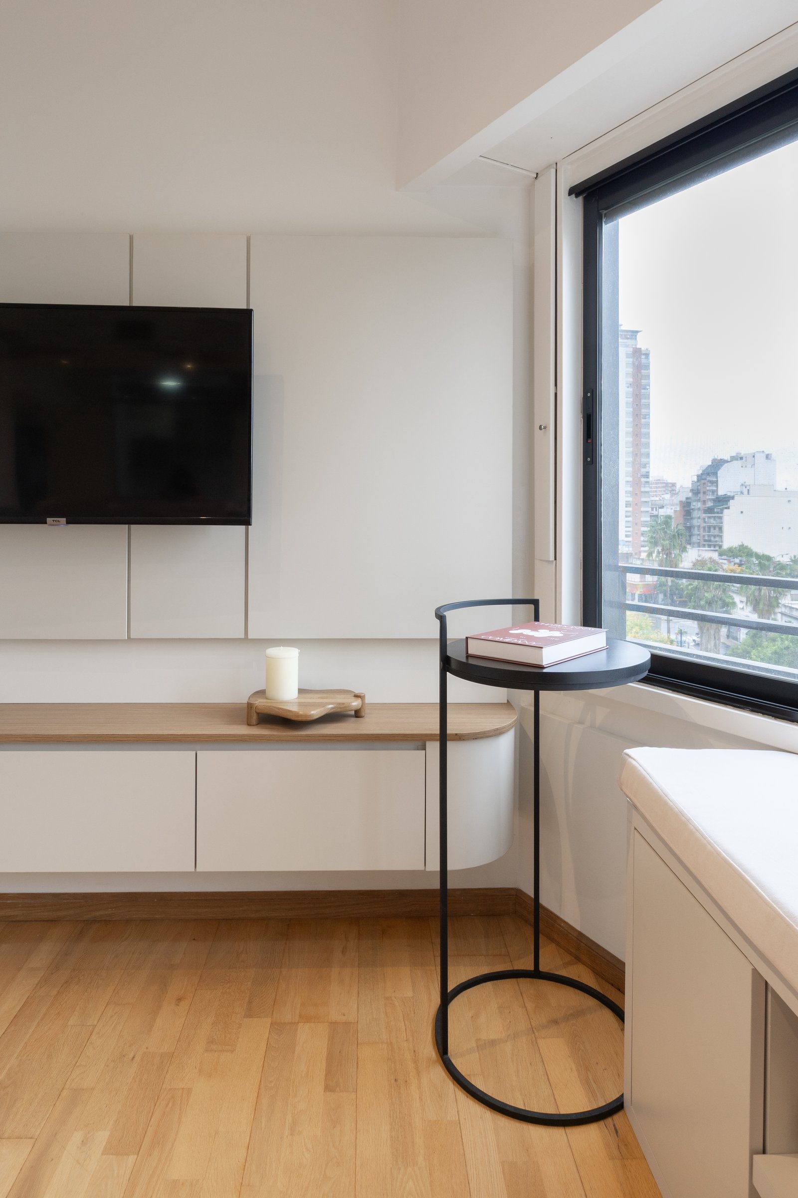 Living moderno minimalista con vista urbana y muebles blancos integrados — proyecto Rio, por Martina Kleinert, en Saavedra