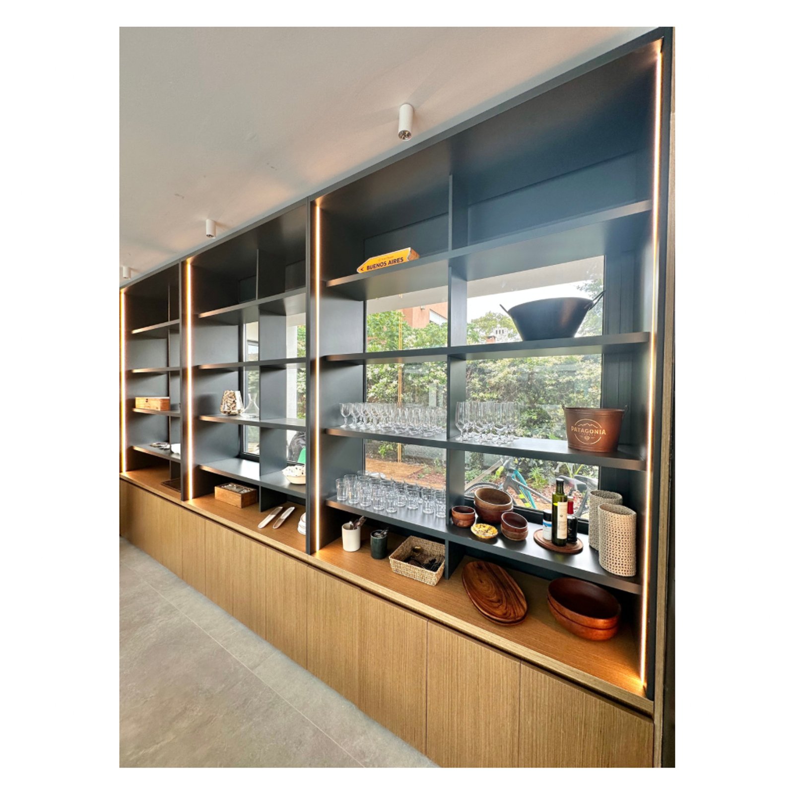 Estantería modular alta negra con iluminación indirecta y muebles de madera — proyecto Pacheco Golf - Estudio Etiqueta, por ABEJA CONCEPT, en Gral. Pacheco