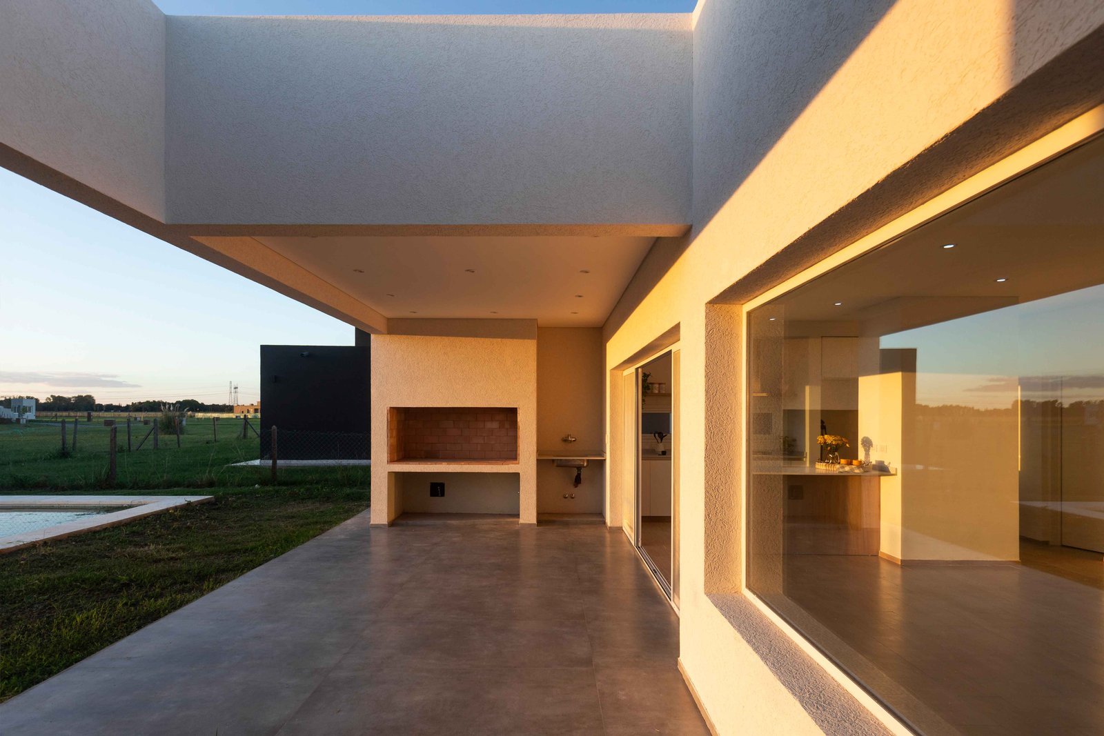 Patio moderno con parrilla integrada y vista al campo — proyecto San Simon I, por Estudio Stepa, en Ezeiza