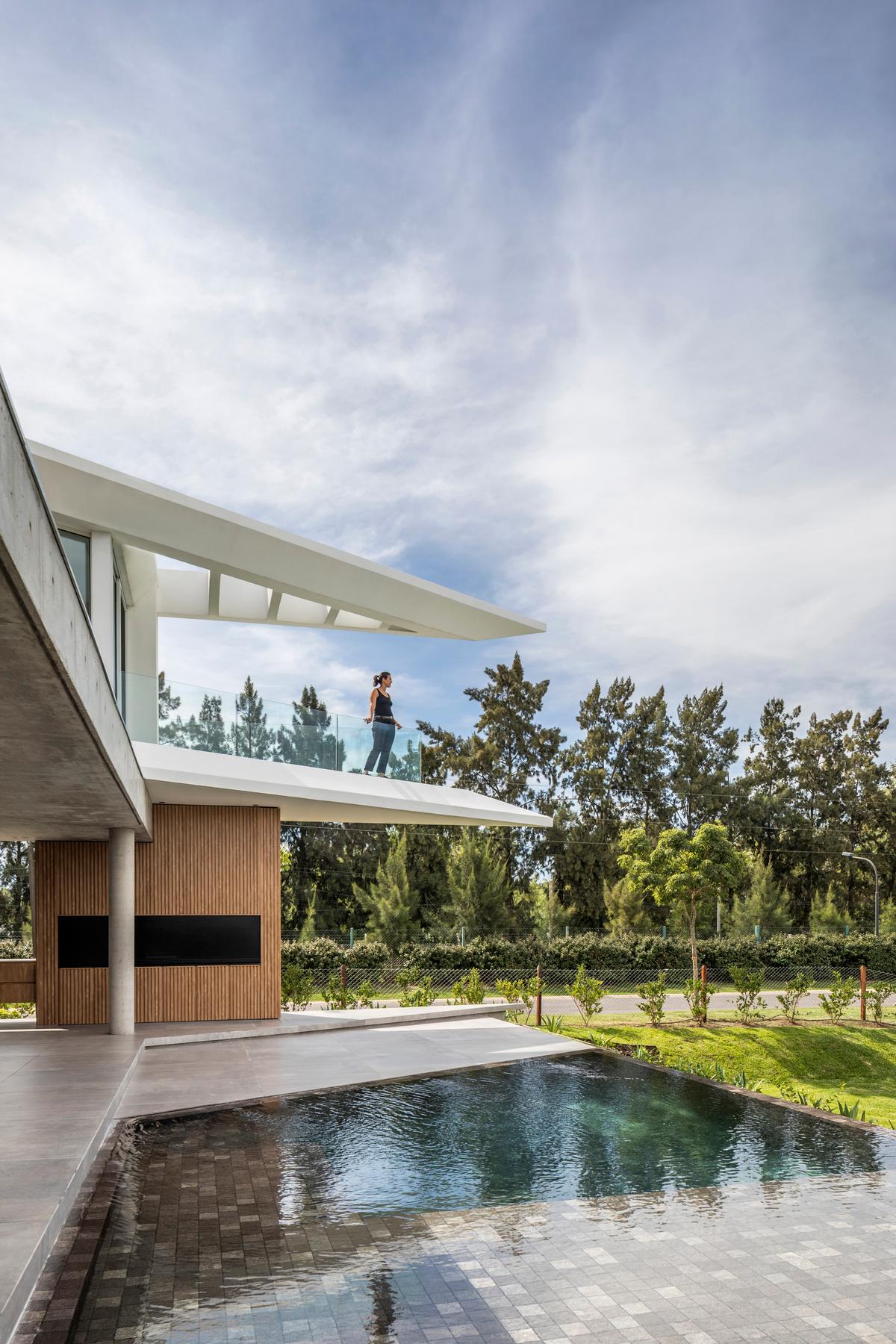 Varanda moderna em balanço com piscina adjacente à vegetação — projeto Casa Didney, por Jorgelina Tortorici & asoc., em Nordelta