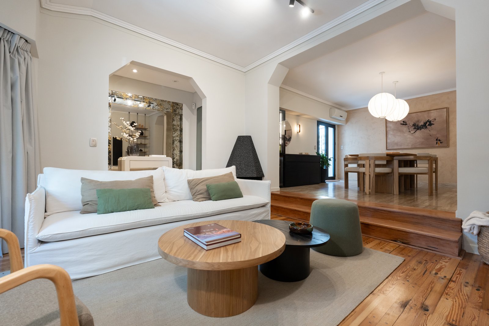 Living y comedor integrados con arcos y pisos de madera — proyecto Felipe Vallese, por Estudio BDM, en Flores