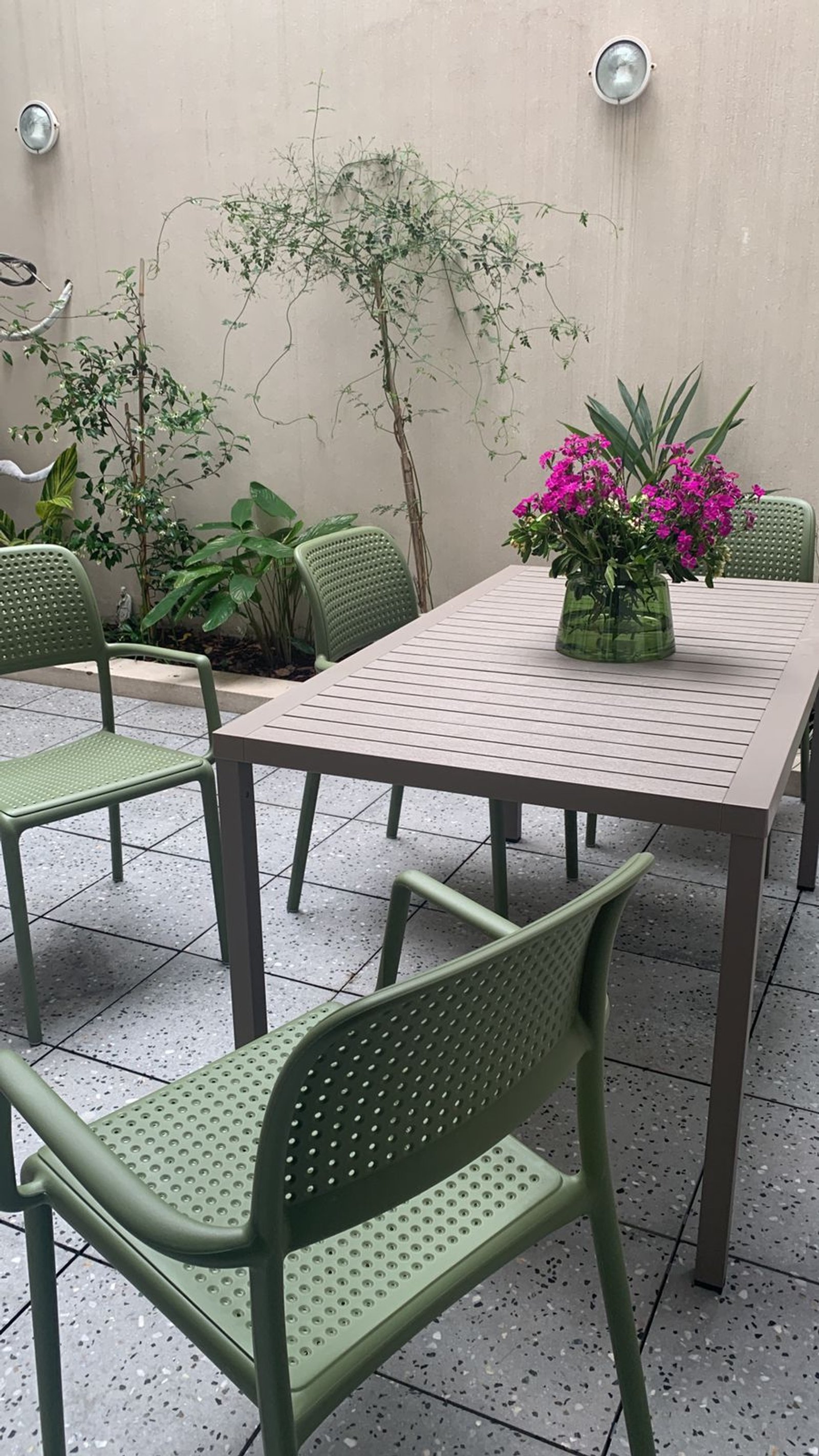Pátio moderno com mesa de metal cinza e cadeiras verdes — projeto Comedor, por Casa Nuñez