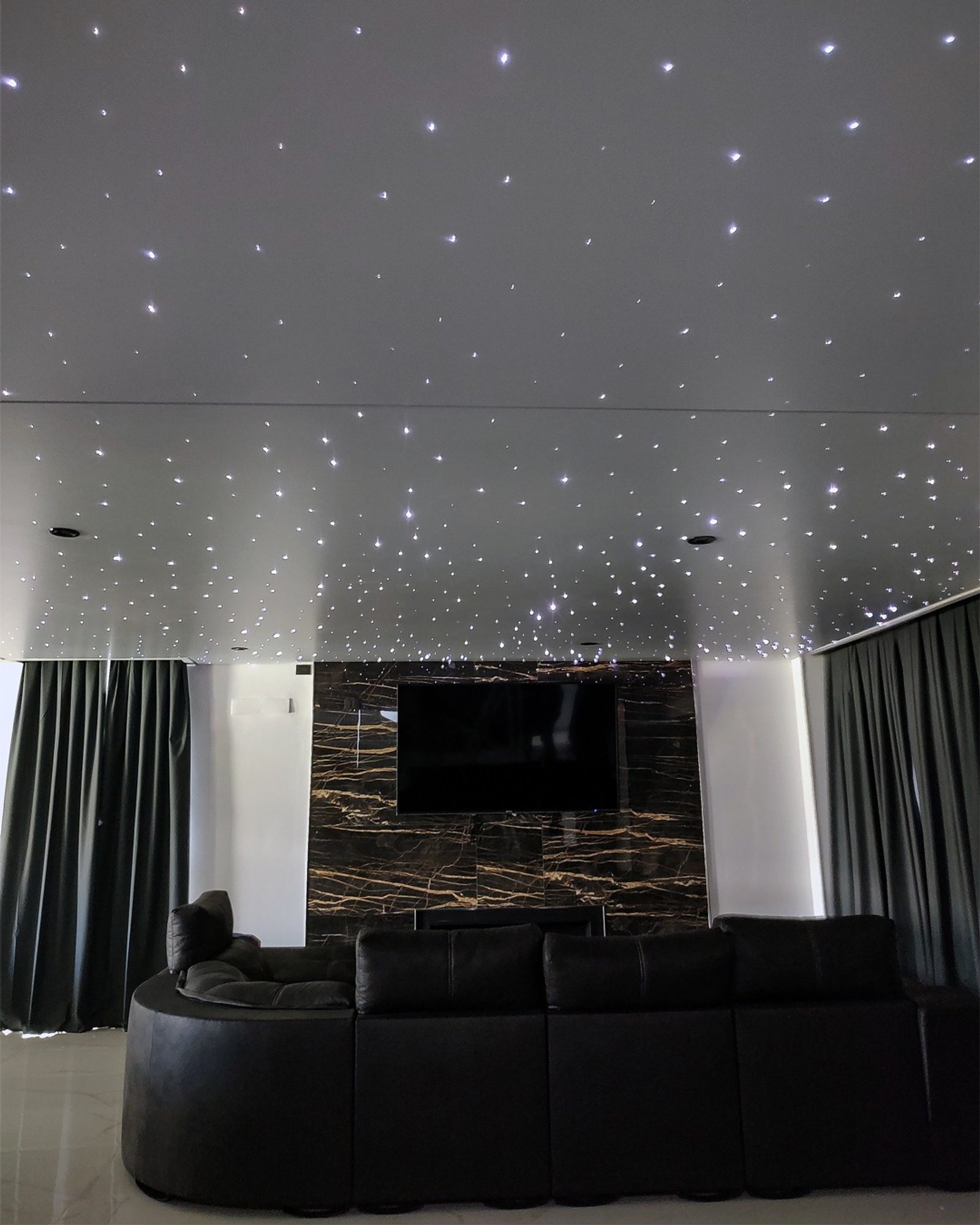 Sala moderna con techo de estrellas y sofá curvo negro — proyecto Cine hogareño , por Clausen deco , en B1648 Tigre