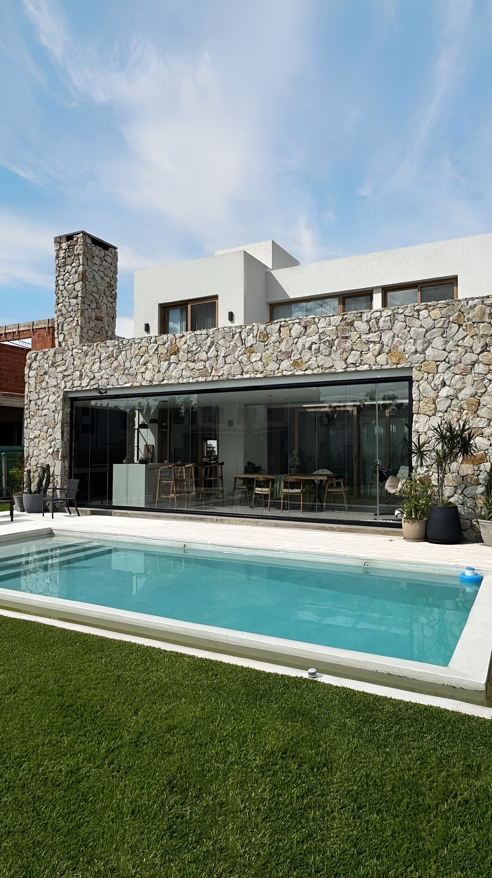 Casa moderna con fachada de piedra y piscina frente al mar — proyecto Casa ER , por Hermann Arquitectos, en Arribeños 1611