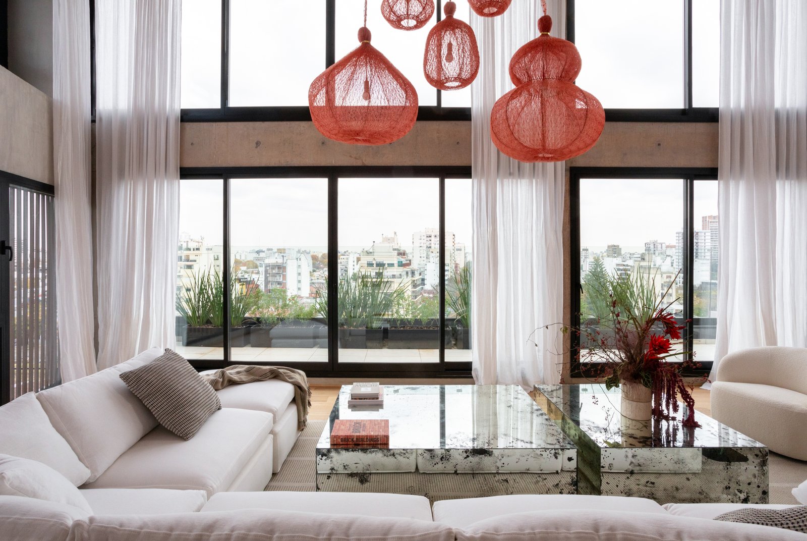 Living moderno de doble altura con vistas urbanas y lámparas colgantes — proyecto Vidal, por Estudio Losa, en Belgrano