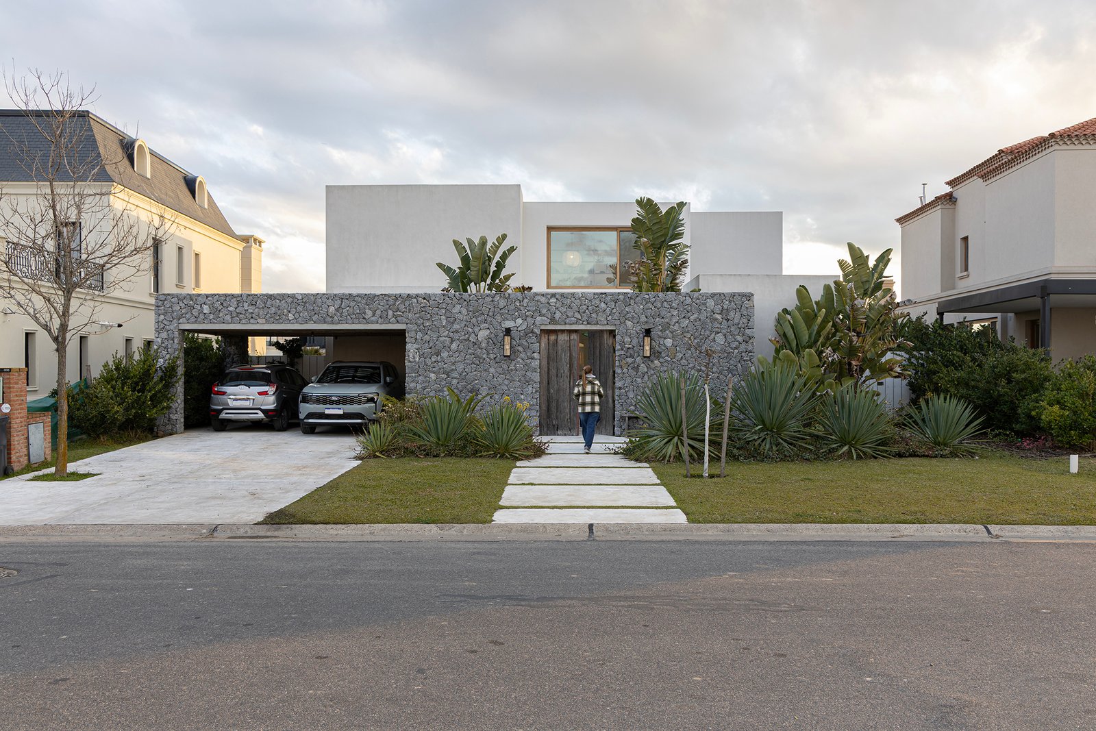 casa moderna con fachada de piedra y vegetación — proyecto Casa Al Agua - Grupo PAUTA, por Gaby Alfonso, en Belén de Escobar