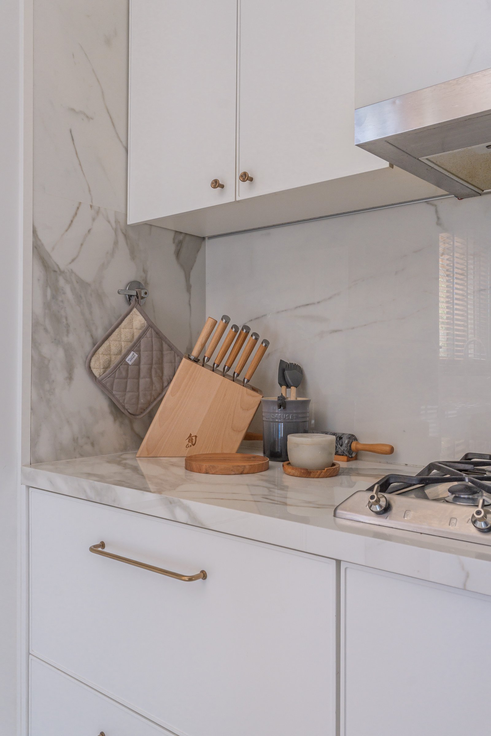 cocina moderna con mármol blanco, gabinetes blancos y detalles dorados — proyecto Pilar A, por Josefina Bertora, en Los Cipreses 2