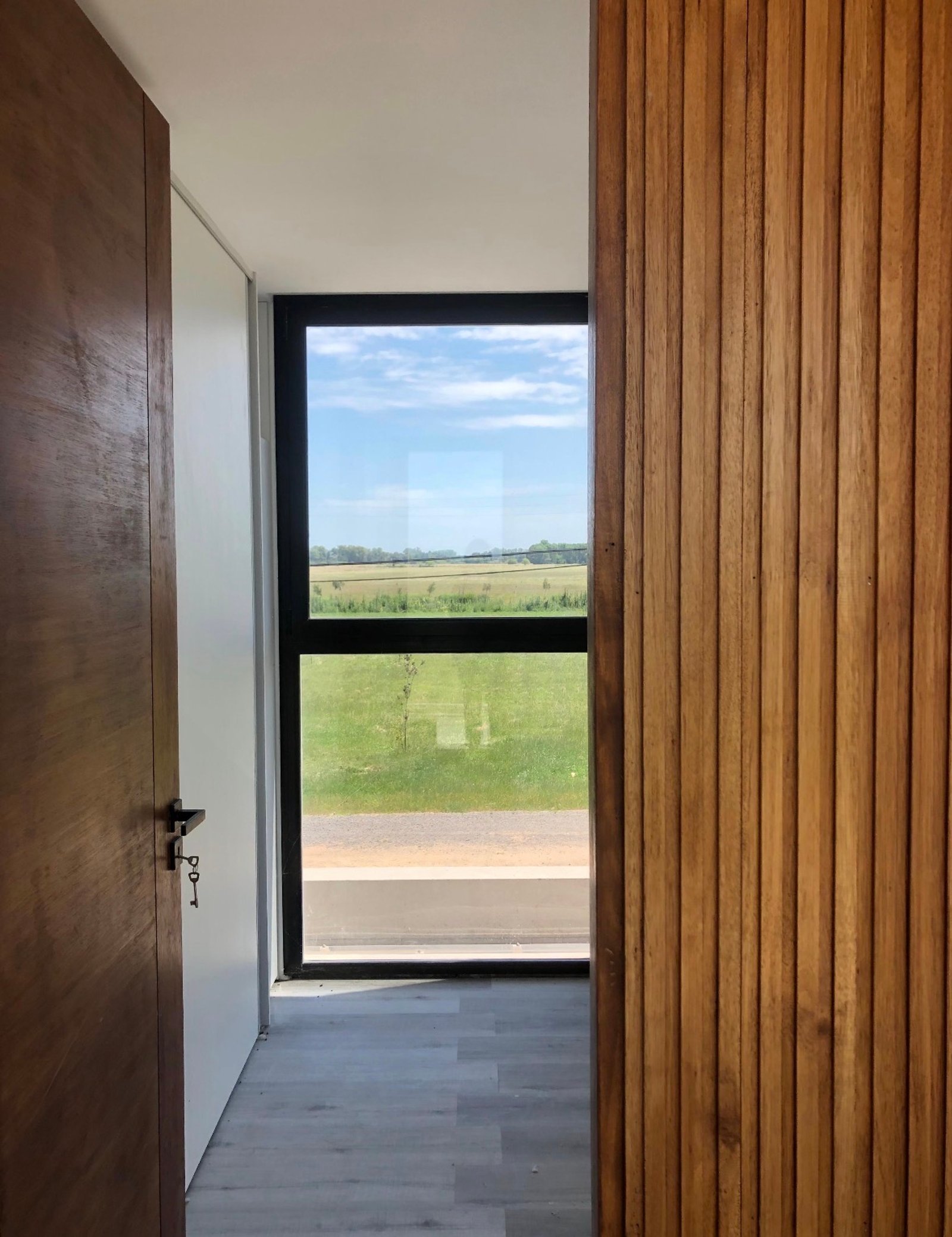 Puerta de madera y pared de listones de madera con vista al campo — proyecto Proyecto Casa Doble, La Plata  , por Estudio cardo, en RP2 2