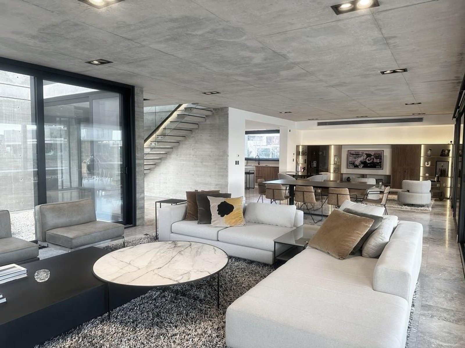 Living moderno con hormigón expuesto y sofá blanco grande — proyecto Espacios, por BURANI, en Martínez