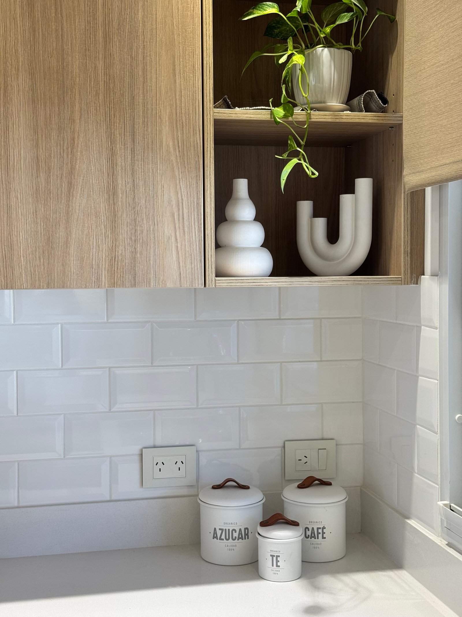Cozinha moderna com azulejos brancos, armários de madeira e acessórios decorativos — projeto CASA M, por Estudio Grupo 32, em Martínez