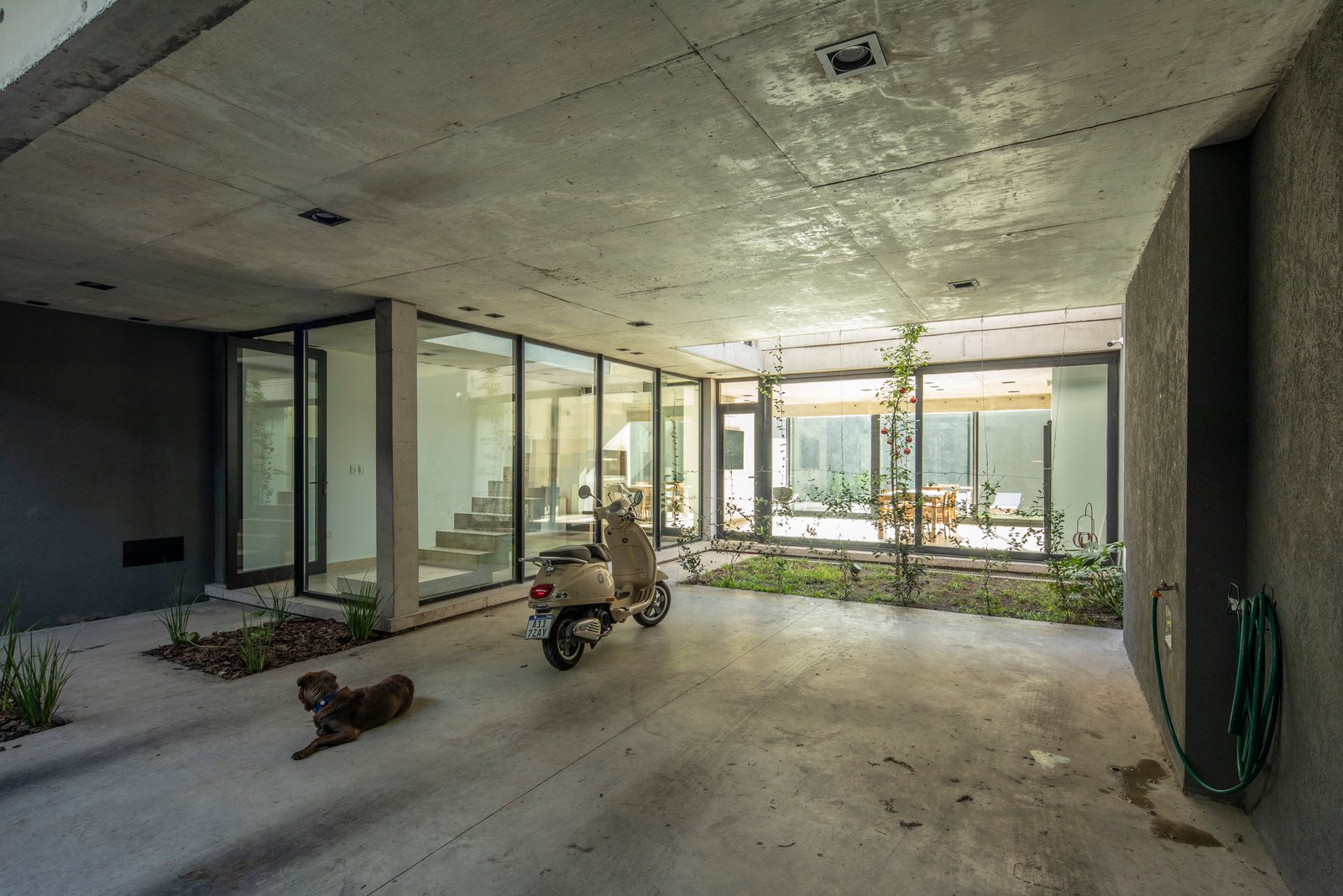 Espacio semi-cubierto de estilo brutalista con hormigón expuesto — proyecto Casa MECHA, por Grupo CRBN, en B1712 Castelar