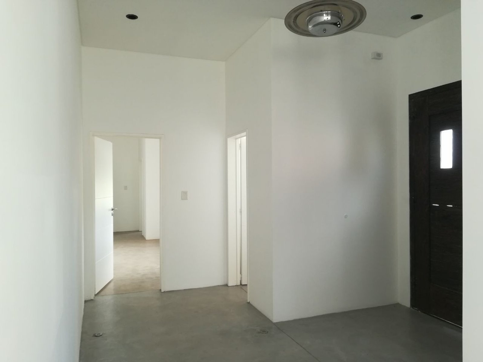 Pasillo interior blanco con piso de cemento gris — proyecto Casa particular en Escobar, por PROTEX, en Belén de Escobar