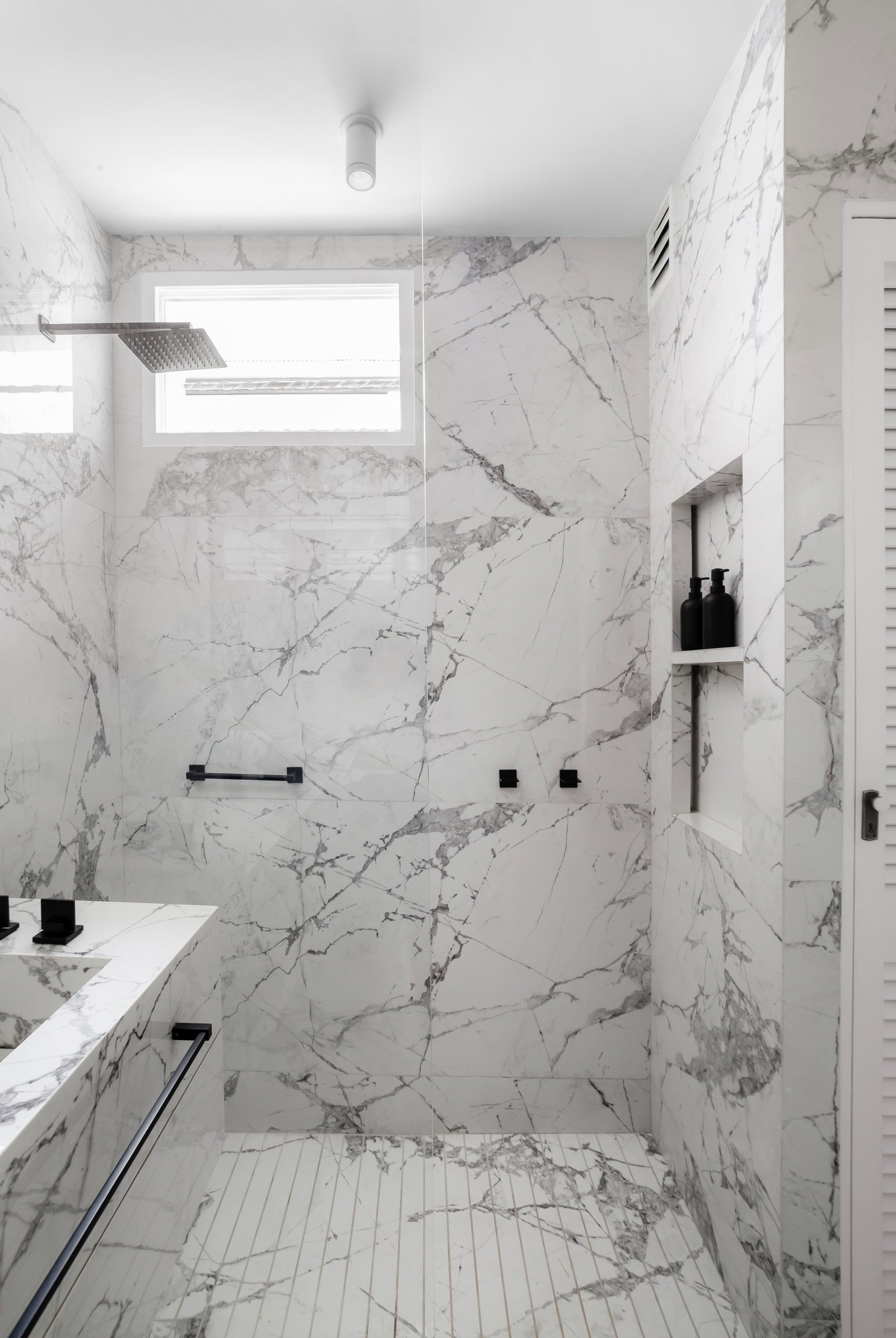 Baño moderno con mármol, ducha de cristal y grifería negra — proyecto Alvear | Redefining luxury, por Ren Studio, en Recoleta