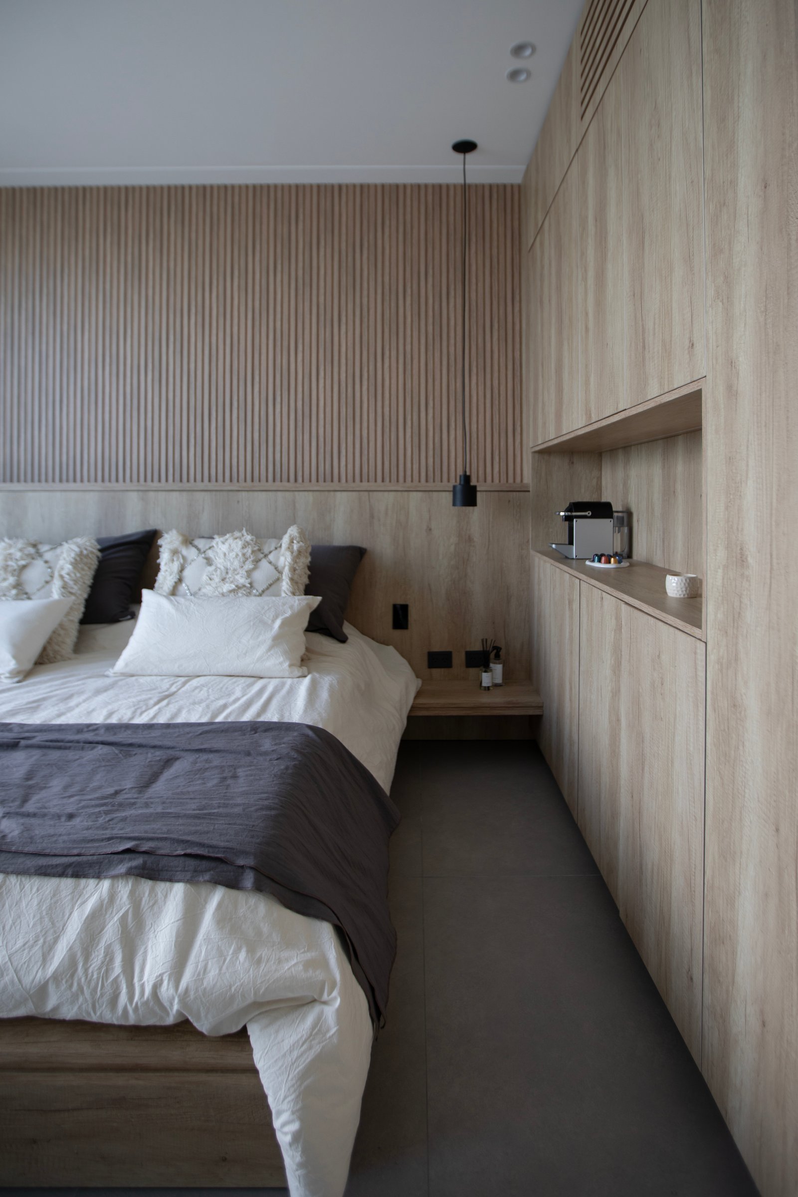 Quarto minimalista com parede de ripas de madeira e mobiliário integrado — projeto CASA TRIBECA CONCRETE BROADWAY, por ILVA, em Provincia de Buenos Aires
