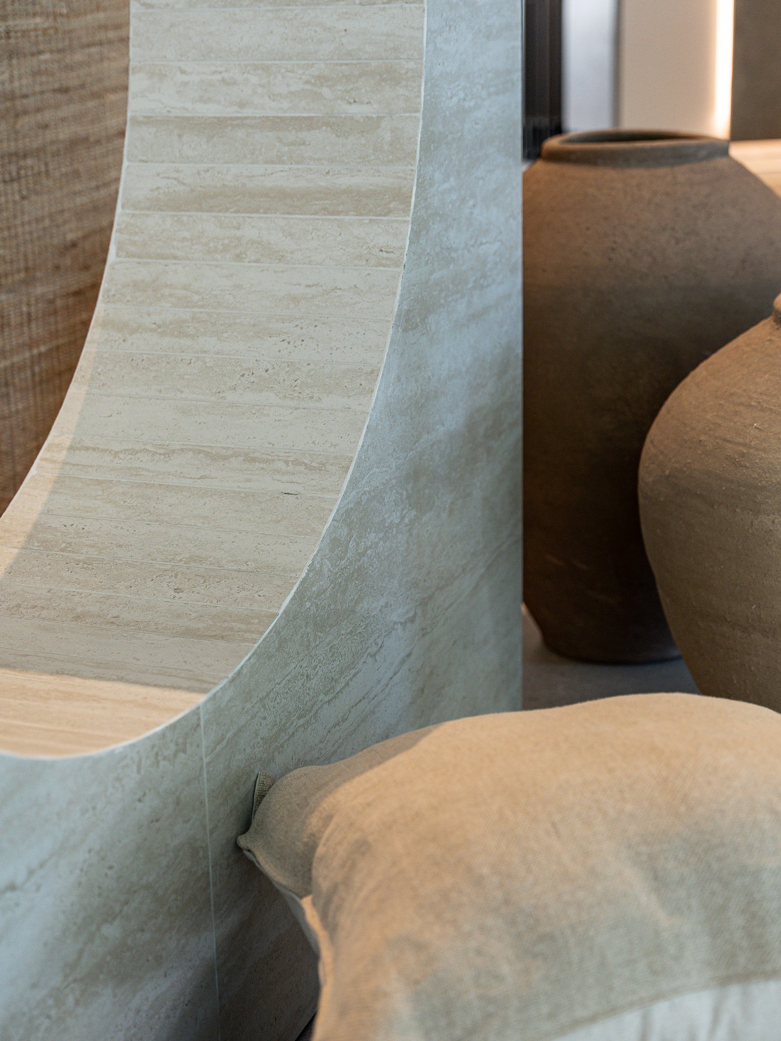 detalle de muro curvo de travertino con jarrón de terracota — proyecto SLD x Rob Ortiz, por San Lorenzo Design, en Showroom con Cita previa