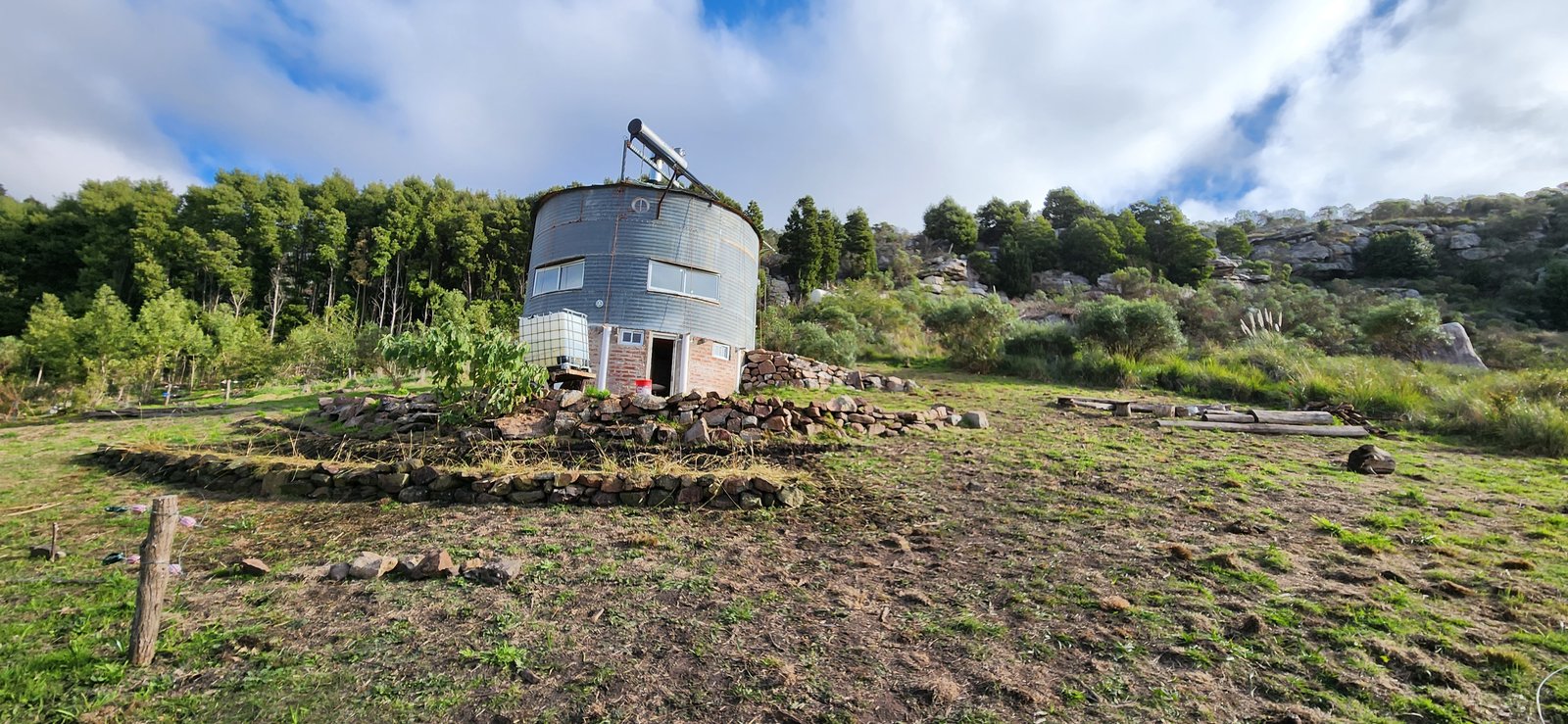 silo metálico redondo en ladera montañosa con vegetación — proyecto Reserva Naural Paititi, por Estudio Rifahi, en Sierra de los Padres