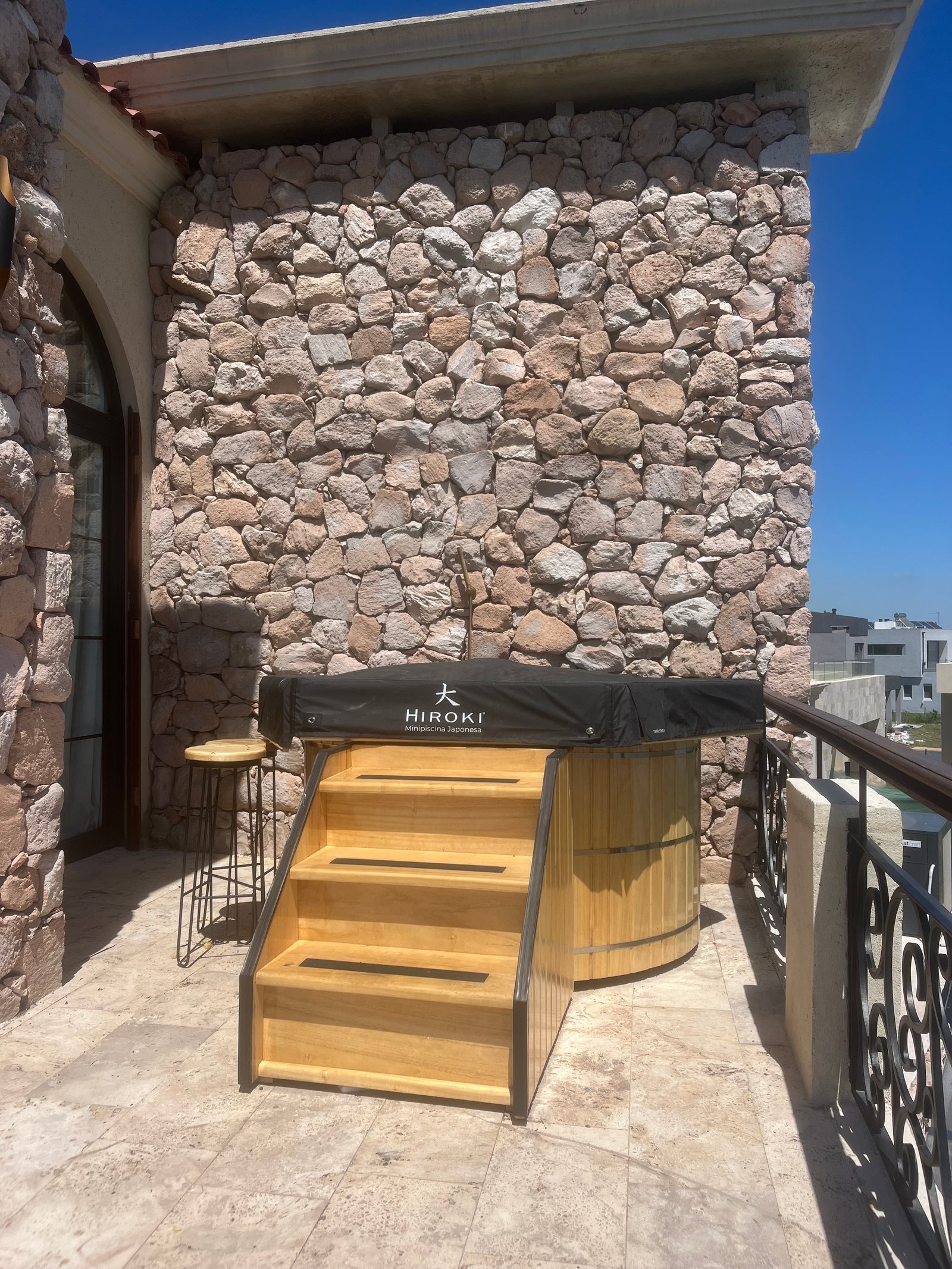 Jacuzzi de madera exterior con escalera y pared de piedra rústica — proyecto casa chacras , por Marianela Grosso, en Papa Francisco 724