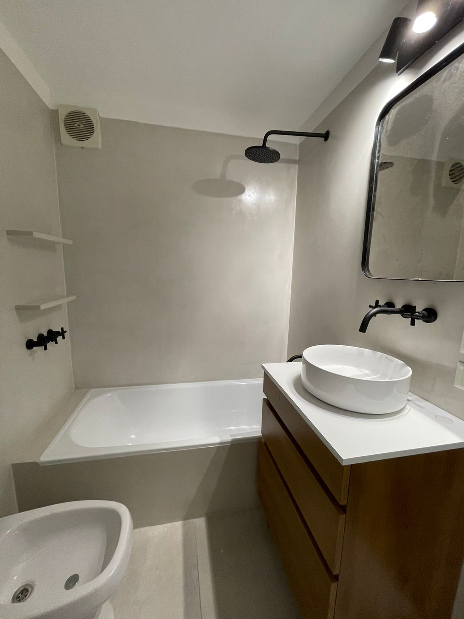 Baño moderno minimalista con revestimiento de microcemento y bañera exenta — proyecto Olazabal, por Estudio NET Arquitectura , en Olazábal 3228