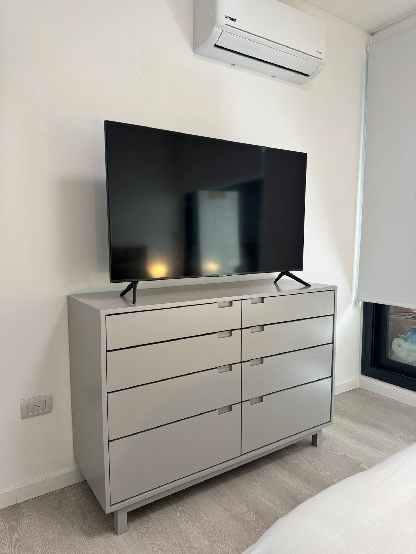 Dormitorio minimalista con cómoda gris y TV — proyecto OM Botanico, por MDBK Arquitectura, en Palermo