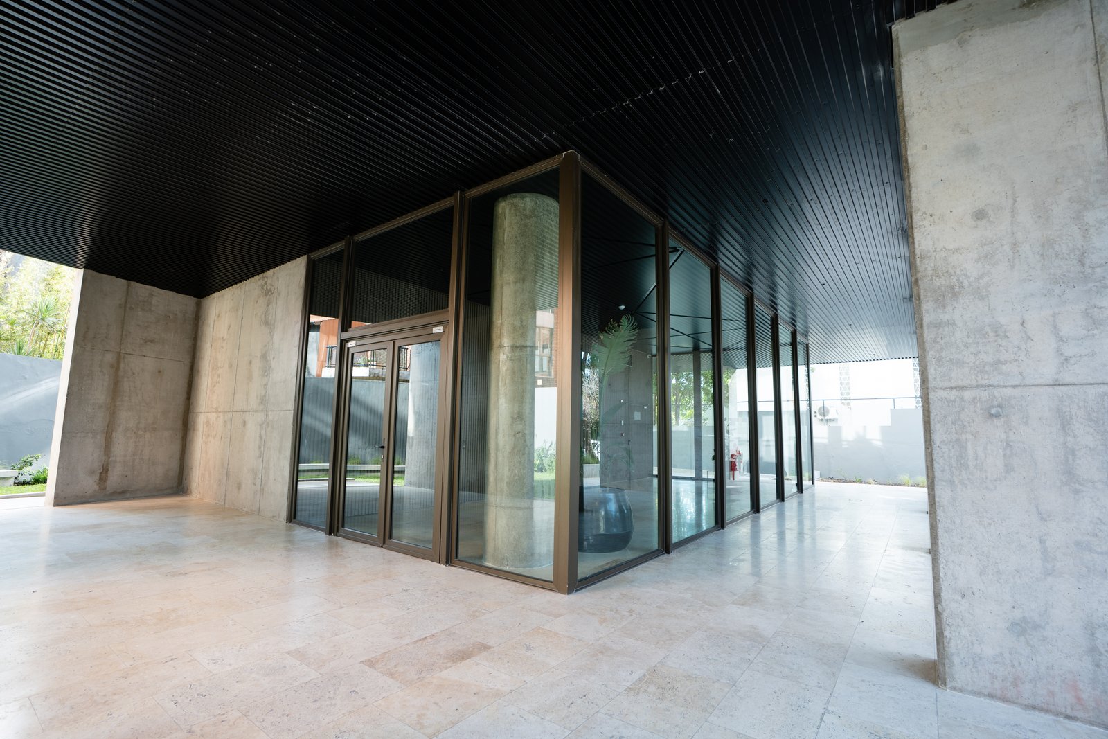 Entrada moderna con gran planta cilíndrica de vidrio y hormigón — proyecto Barlovento Towers, por MUCHTEK, en La Lucila