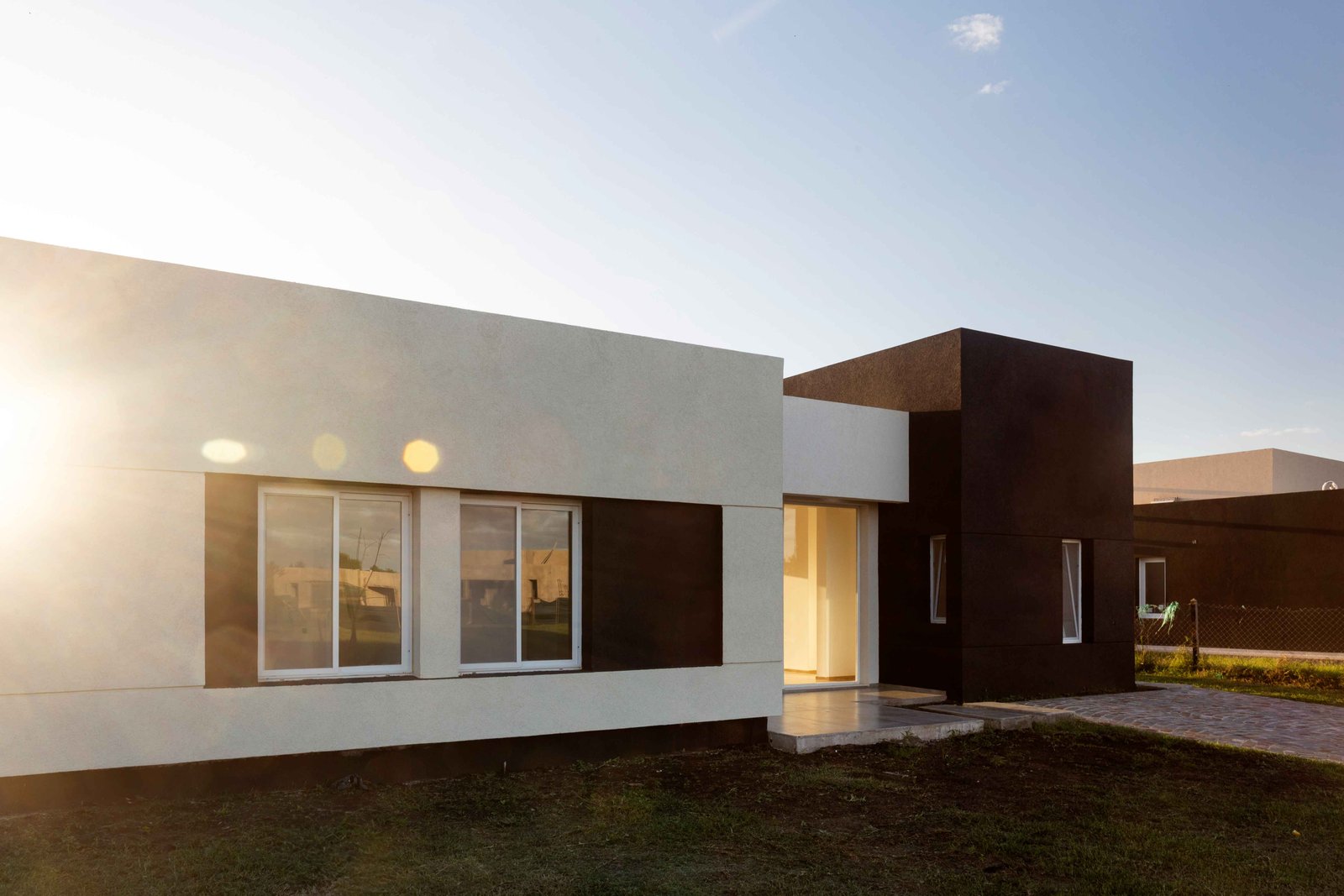 Fachada de casa suburbana moderna com linhas limpas — projeto San Simon I, por Estudio Stepa, em Ezeiza