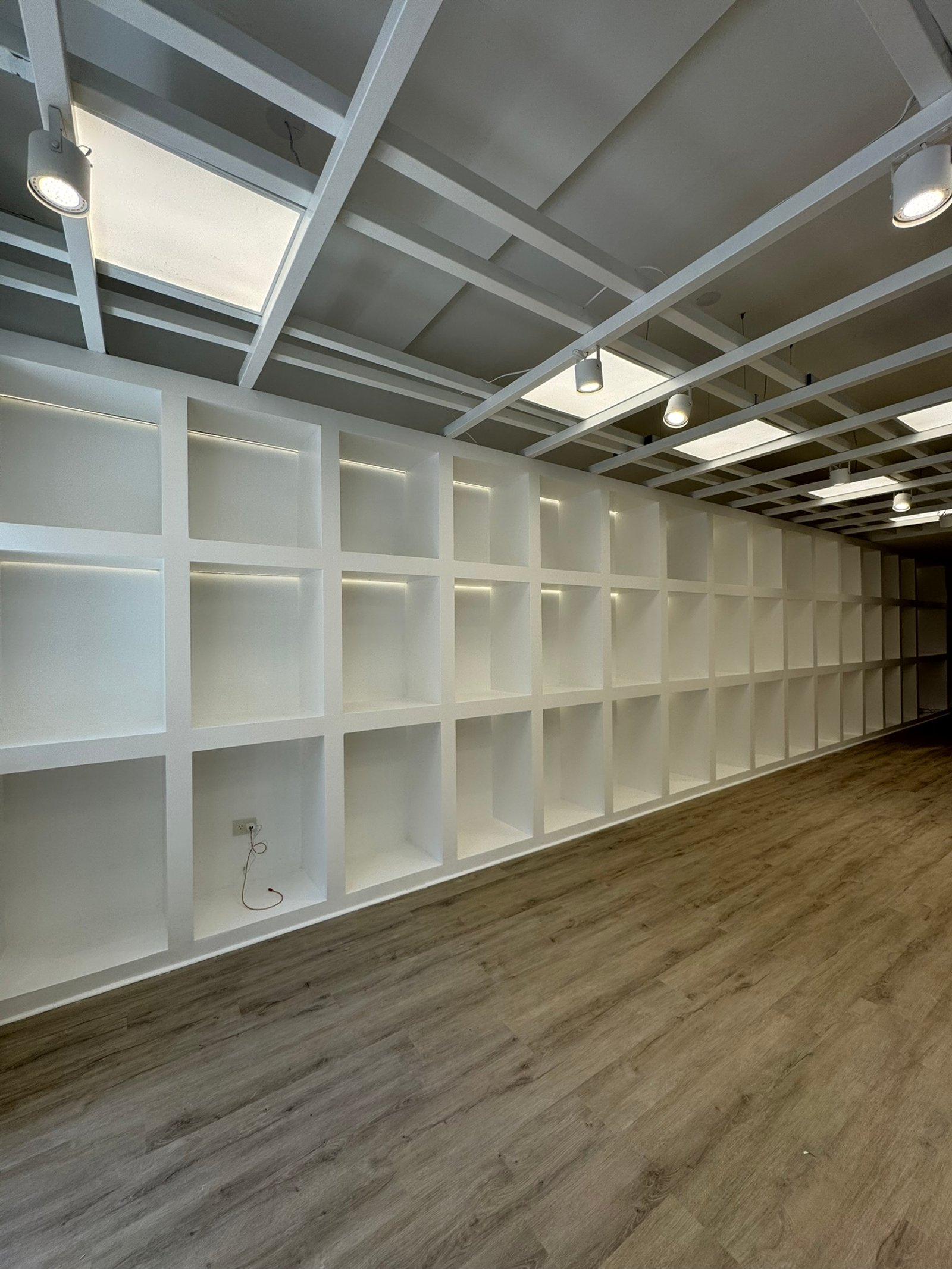 Espaço comercial minimalista com prateleiras modulares brancas — projeto Leonardo Marroquinería, por MDBK Arquitectura, em Balvanera