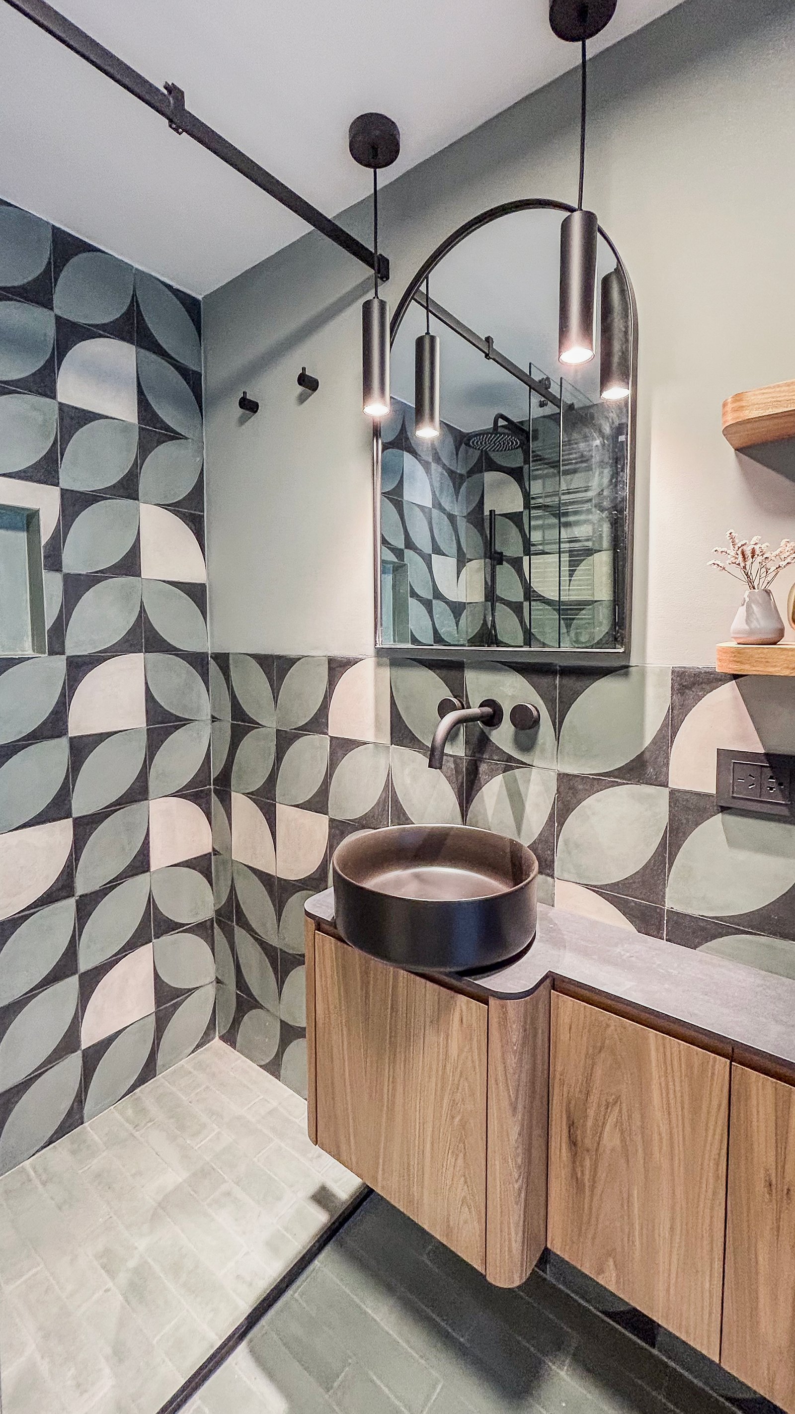 Baño moderno con lavabo de cerámica negra, vanitory flotante de madera y espejo arqueado — proyecto Al Río - Baño, por Blue Rabbit Design, en Vicente López