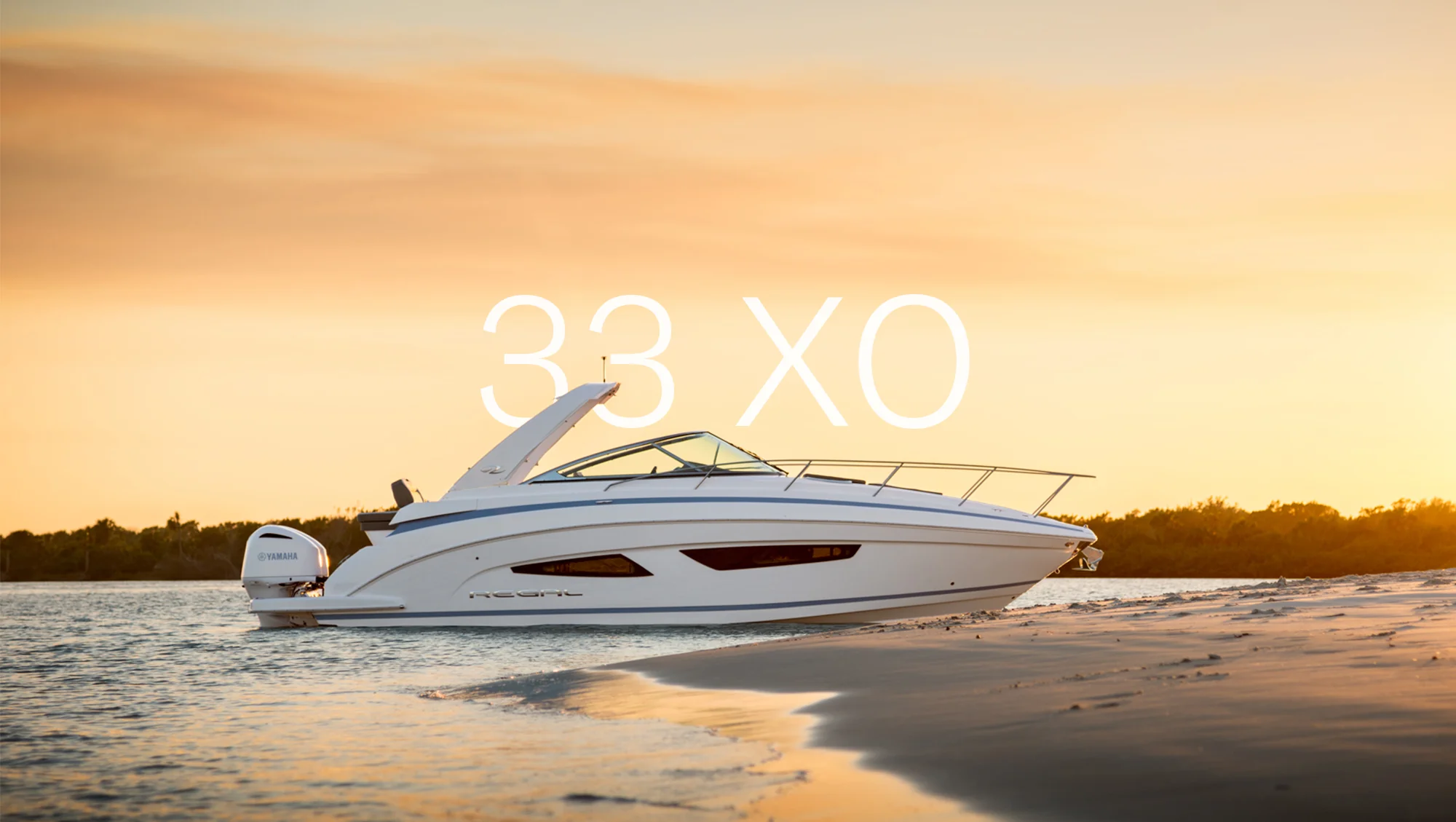 Regal 33 XO przy brzegu w szerokim kadrze hero o zachodzie słońca.