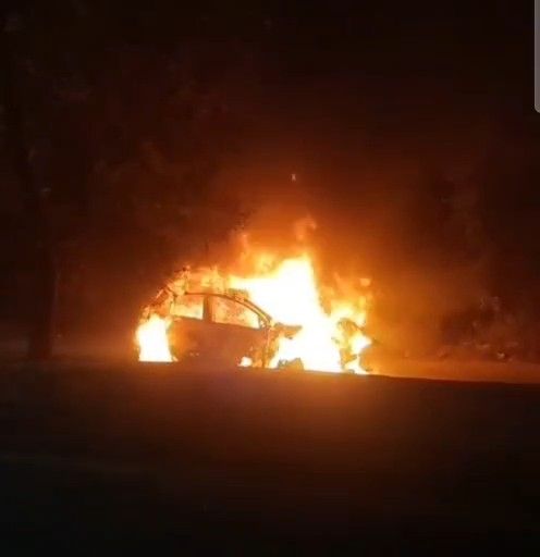 आगरा के जगदीशपुरा में शॉर्ट सर्किट के कारण जलकर खाक हुई कार का मलबा और पास में मौजूद पुलिस बल।