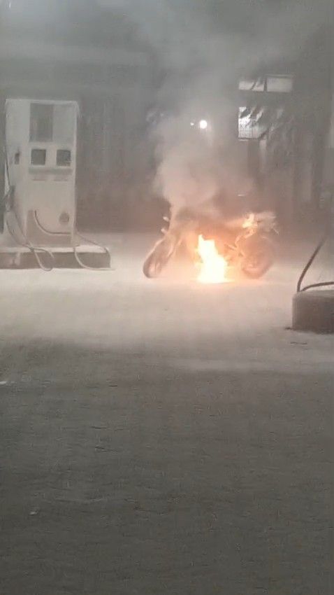 उत्तर प्रदेश के हमीरपुर में सुमेरपुर पेट्रोल पंप पर जलती हुई मोटरसाइकिल और आग बुझाते हुए कर्मचारी।