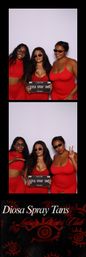 Three women in matching red outfits and sunglasses pose in a photo booth in Austin, Texas, holding a license-plate style spray-tan sign, smiling and making playful faces.