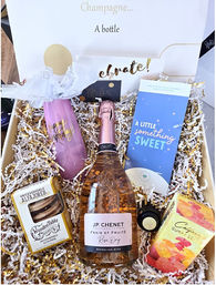 Birthday celebration gift box with a rosé sparkling wine bottle, pink "Happy Birthday" tumbler, chocolate bar, cookies and gummy candies nestled in gold-and-white shredded paper