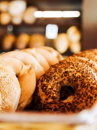 Close-up of golden sesame and everything bagels in a bakery display, fresh and crunchy with toasted seeds