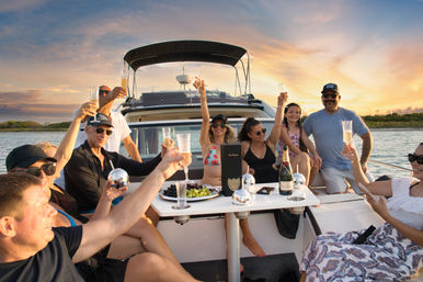 Friends toasting champagne on a luxury yacht at sunset during a coastal cruise with a fruit platter