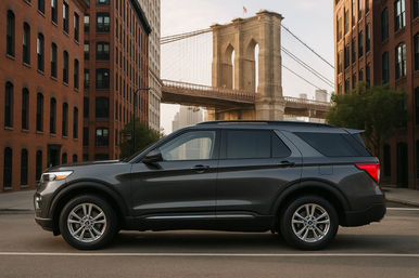 Sleek dark gray SUV parked between red-brick buildings with the Brooklyn Bridge and New York City skyline glowing in the background.