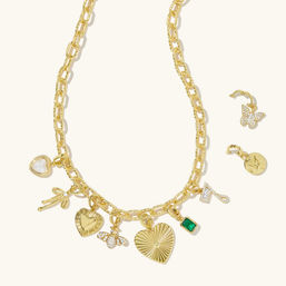 Gold charm necklace on a cream background featuring a chunky chain with mixed pendants — ribbed heart, small heart, pearl heart, bow, crystal bee, emerald-green stone and a crystal '7', with separate butterfly and star-coin charms — women's fashion jewelry, gift-ready.