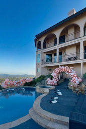 Hillside villa pool and patio with mountain view, pink and rose-gold balloon garland and 'BRIDE' balloon arch for a bachelorette celebration.