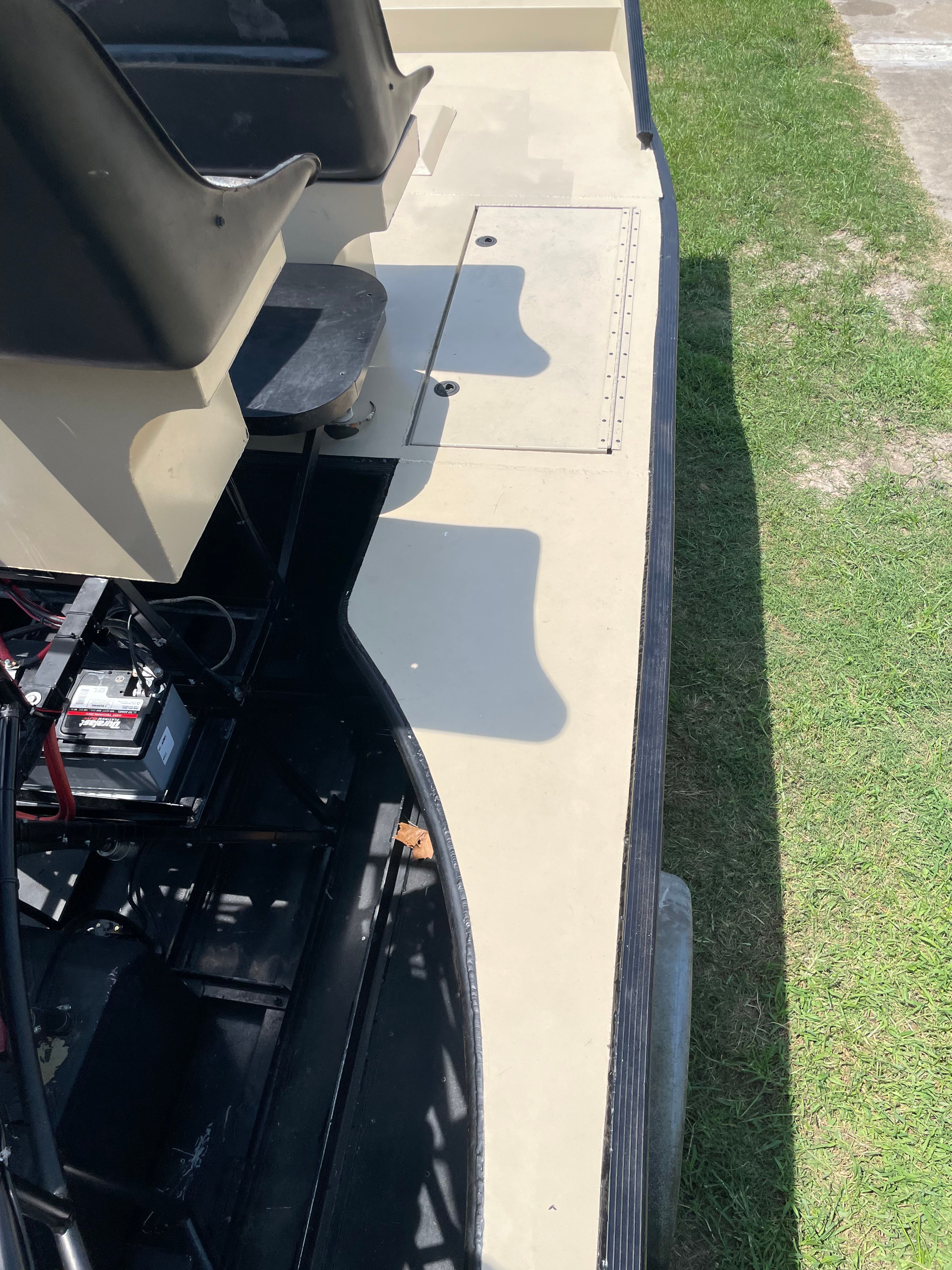 Airboat deck with black bucket seats and battery compartment