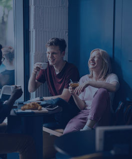 Two young men and a woman are sitting in a café and talking