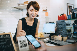 Cashier in a Chinese café. A customer is scanning the merchant's QR code at the counter