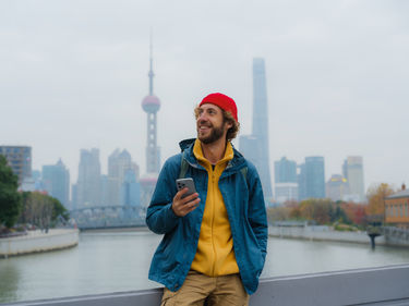 Traveller with smartphone in front of the Shanghai skyline