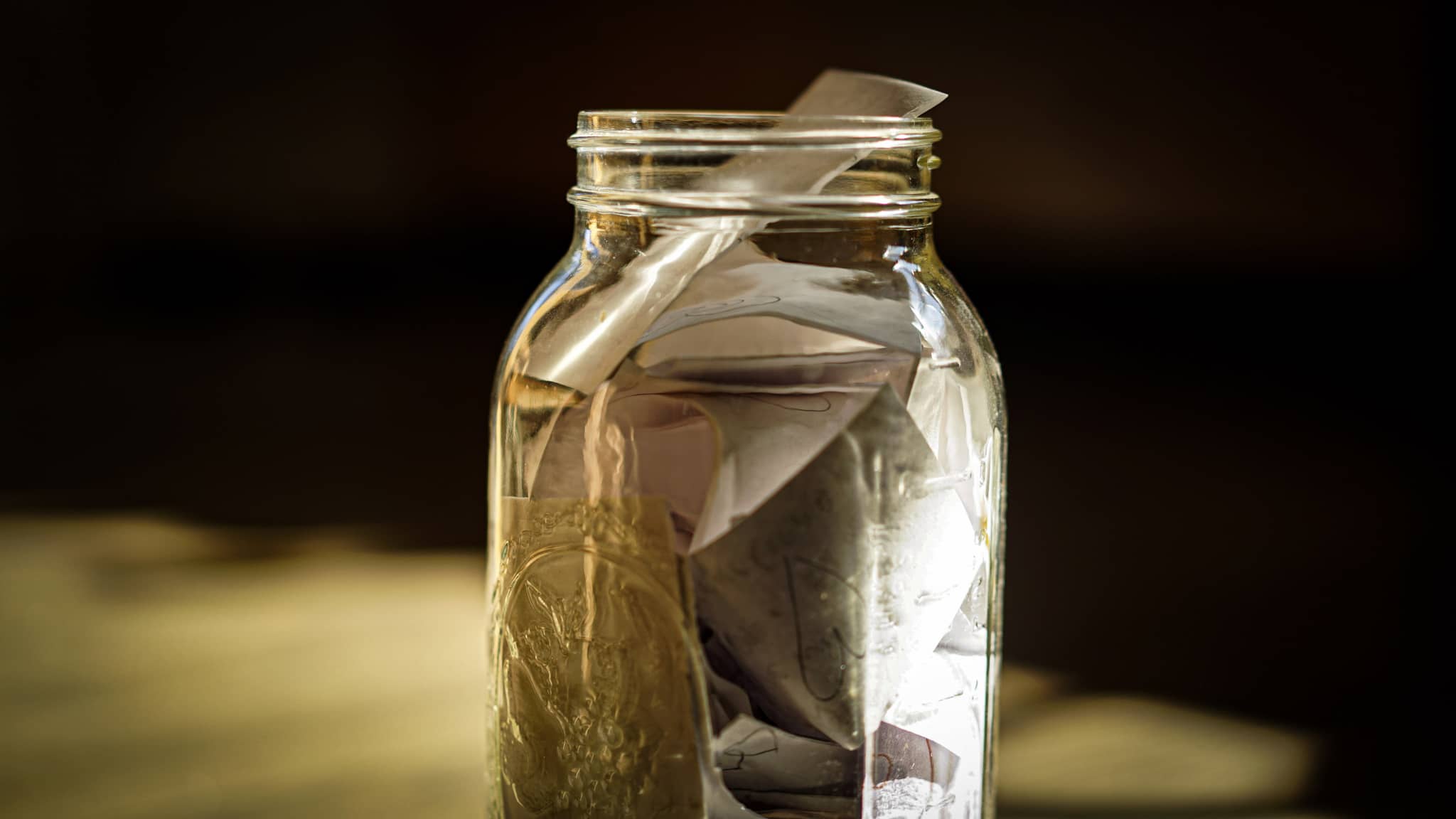 A glass jar full of slips of paper, each one carrying a note from family members and loved ones