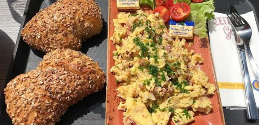 Frühstück in Peters gute Backstube, zu sehen sind zwei Brötchen und Rührei