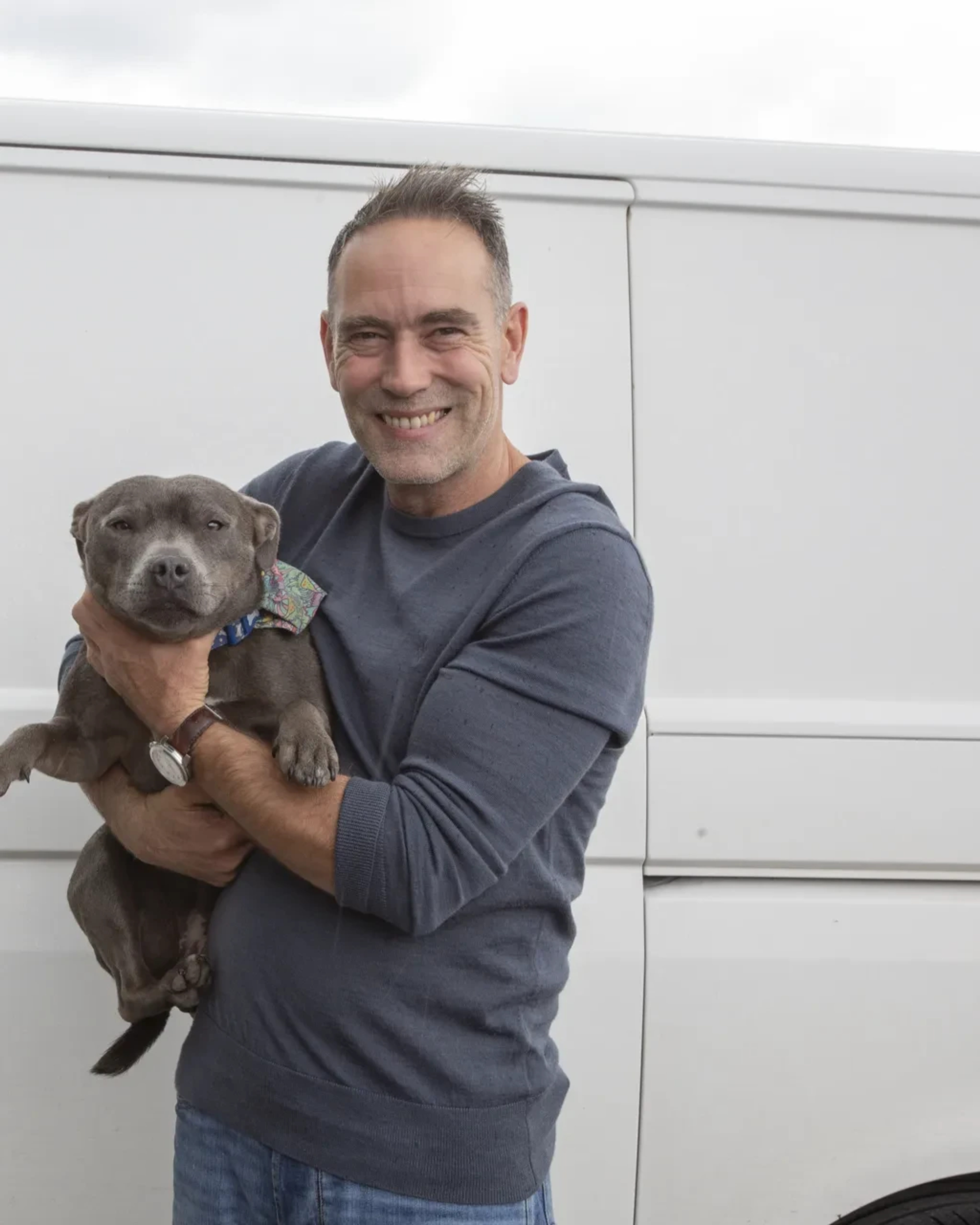 Wayne Ross, owner of Clear House Moves, holding his dog in front of a company van